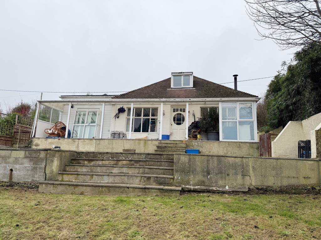 Lot: 128 - DETACHED CHALET-STYLE HOME WITH STRUCTURAL MOVEMENT ON A PLOT OF 0.17 ACRE - Looking at the dwelling from the garden